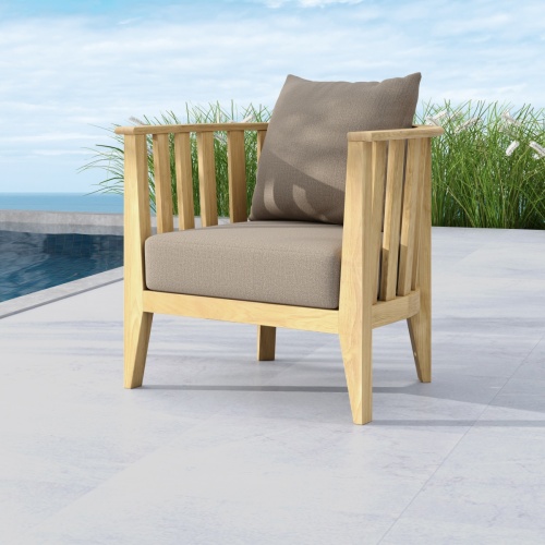 12170dp Kafelonia teak club chair with cushions side angle outside on concrete patio with pool and ocean in background