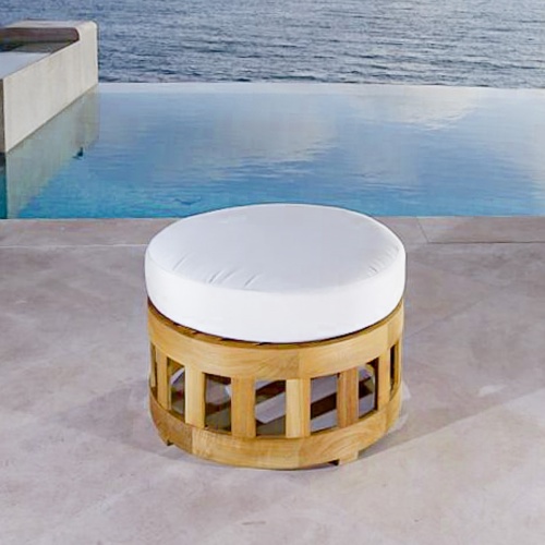 18170 Kafelonia teak coffee table ottoman with canvas colored cushion on concrete patio with infinity pool and ocean in background