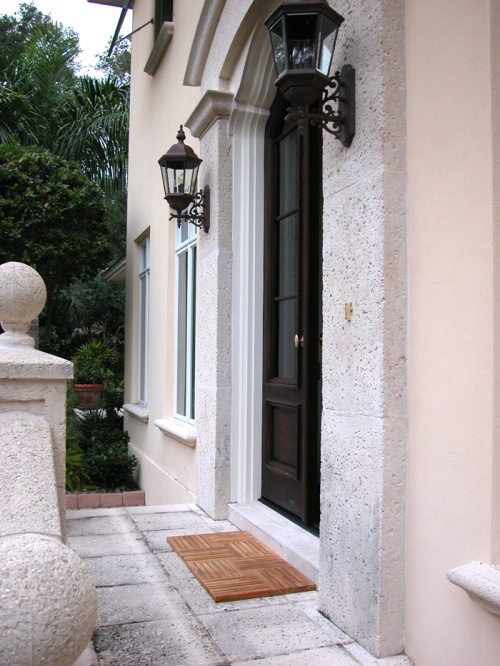 18412DM Parquet Teak Door Mats by an entry door on concrete patio with shrubs in background
