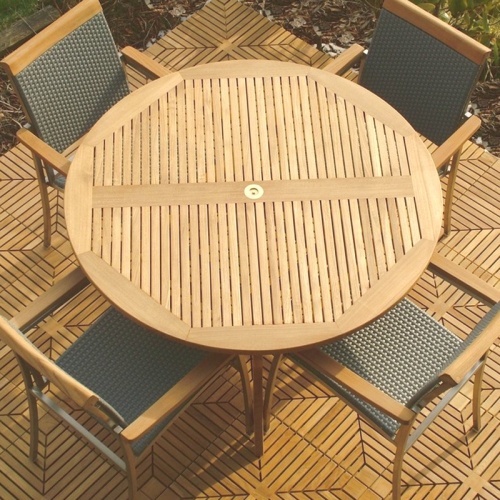 70030 Grand Hyatt SS Kelly Dining Set of a 48 inch round dining table and 4 SS Kelly dining chairs angled aerial view on optional teak tile flooring with shrubs and mulched background