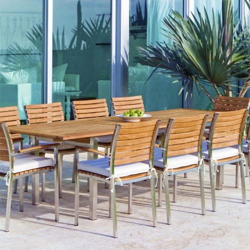 70055 Vogue 11 piece teak and 304 stainless steel dining set with optional seat cushions plate of green apples on outdoor lanai with glass doors and palmetto palm in background