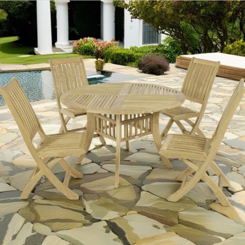 70056 Hyatt Barbuda teak 5 piece Dining Set of Hyatt 4 ft round Dining Table and 4 Barbuda folding teak chairs on stone pool deck surrounded by plants and trees with pool and house in background