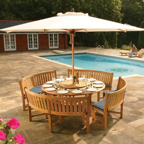 70067 Buckingham teak Curved Bench Dining Set open market umbrella teak lazy susan two wine bottles table setting on pavers pool and house in background