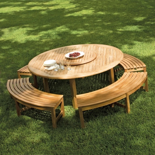 70090 Buckingham Picnic Dining Set showing teak lazy susan with bowl of grapes in center umbrella hole and stack of plates silverware napkins on grass field