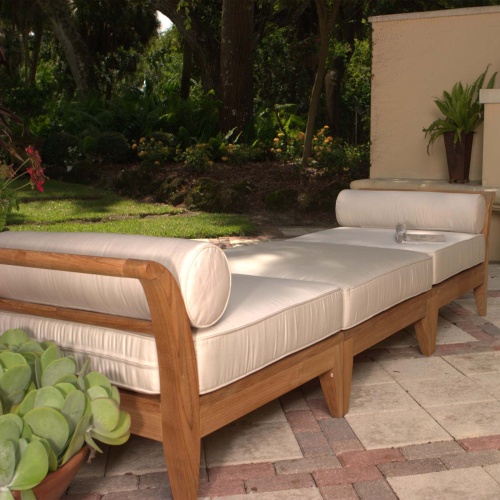 70103 Aman Dais 3 piece teak set on stone patio angled with two potted plants on both sides of daybed with landscaped area in background