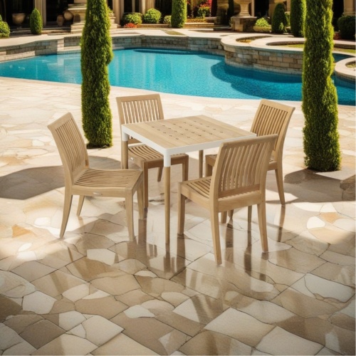 70104 Bloom Laguna 5 piece Dining Set of Bloom 32 inch square table and 4 Laguna Side Chairs on pool deck with pool and cypress trees and landscaping plants in background 