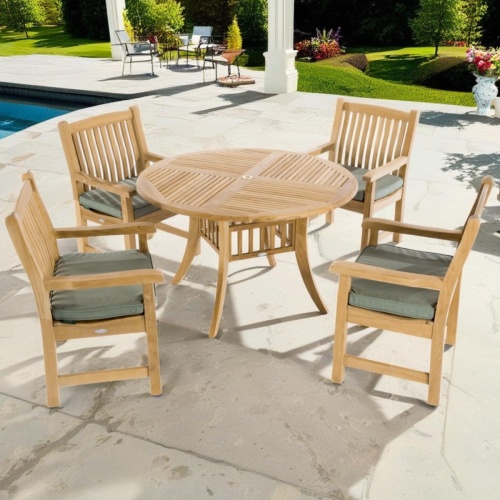 70159 Hyatt Veranda 5 piece teak Dining Set of 4 armchairs and round 48 inch diameter table angled aerial view on pool deck with pool and landscaping plants and trees in background 