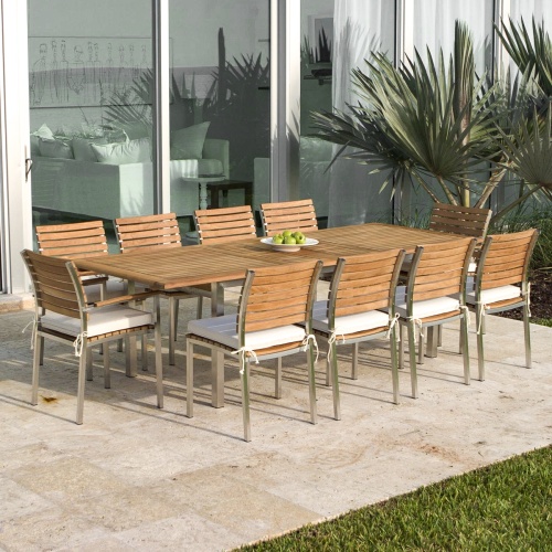 70176 Vogue stainless steel and teak rectangular dining set for ten with optional seat cushion white plate of green apples on concrete patio palmetto palm and glass door in background
