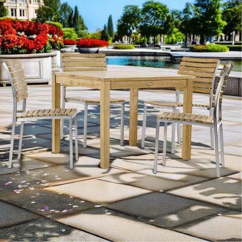 70426 Vogue 5 piece Cafe Set of 4 teak and stainless steel side chairs and 36 inch square table on concrete terrace surrounded by flowering plants overlooking a canal in background 