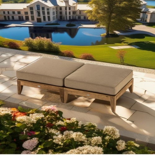  70433 aman dais teak ottoman sectional Set with cushions showing 2 in side view on stone terrace surrounded by flowering plants overlooking a home with lake and green grass in background
