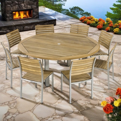 70444 Vogue 9 piece teak and stainless steel Dining Set of 8  Vogue side chairs and Vogue 72 inch diameter round dining table side view on pavers patio surrounded by flowering plants and trees with lake in  background    