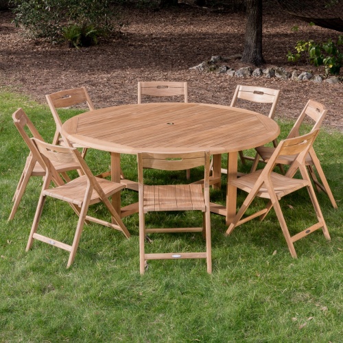 70454 Surf Buckingham 9 piece round Dining Set of 8 folding chairs and 72 inch round dining table on grass lawn with mulched landscape area with trees in background
