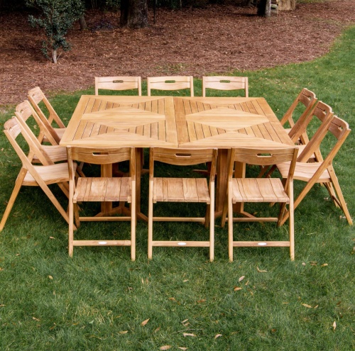 70458 Surf Pyramid 14 piece Dining Set shown with 12 dining chairs and 2 rectangular teak dining tables on grass lawn with mulched area with trees 