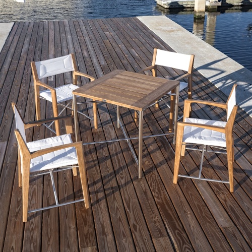 70459 Odyssey 5 Piece folding teak and stainless steel dining set of  Odyssey 32 inch square dining table and 4 Odyssey folding chairs on boat dock next to a boat marina 
