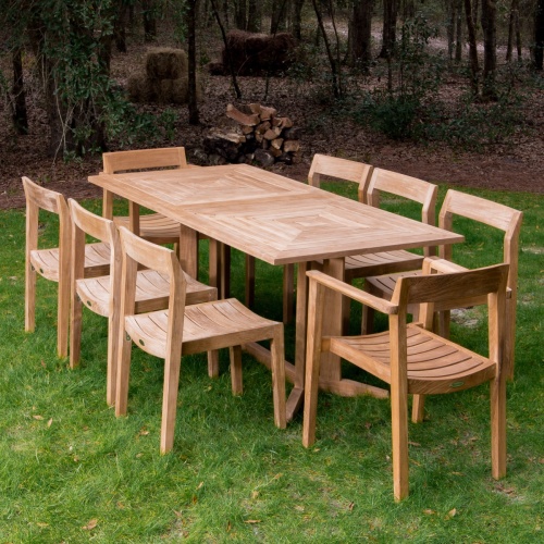 70462 Pyramid Horizon nine piece teak dining set on grass field with trees and brown mulch in background