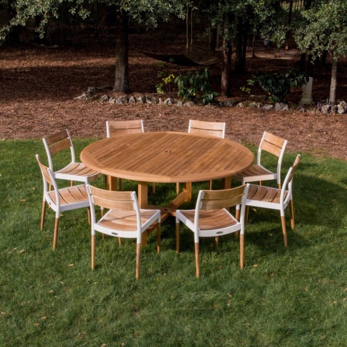 70470 Bloom Buckingham teak 9 piece Dining Set of Buckingham teak 60 inch round dining table and 8 Bloom teak and aluminum side chairs on grass lawn with trees and plants in back