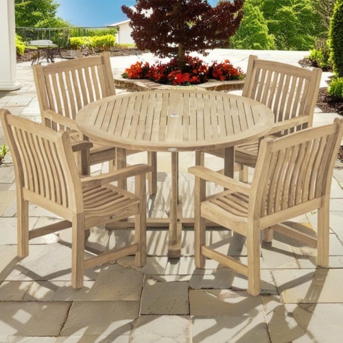 70483 Veranda teak 4 ft Round Dining Set of 4 Veranda Teak Armchairs and 4 foot round teak dining table with plants and trees and blue skies in background 