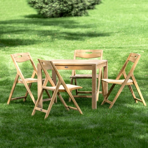 70513 Surf teak 5 piece 36 inch square Dining Set of 4 teak folding side chairs and teak 36 inch square dining table on grass field with tree in background