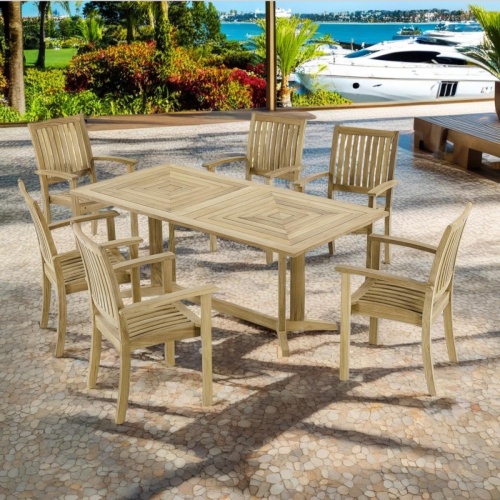 70517 Sussex Pyramid teak 7 piece Dining Set angled side view on patio showing plants trees and grass in back with yachts docked in waterway in the background