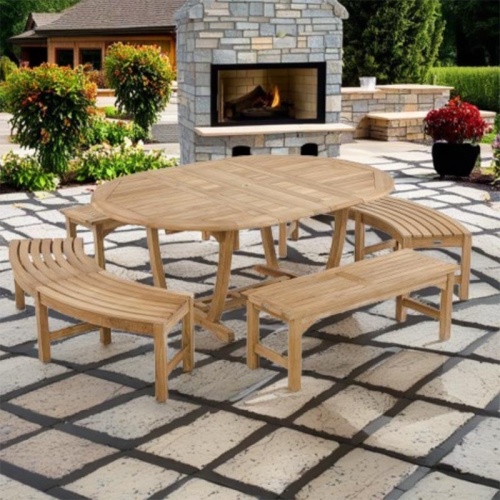 70523 Martinique Bench Dining Set of Martinique teak oval Dining Table and 2 backless benches and 2 curved backless benches angled on stone patio with fireplace and potted plants in background 