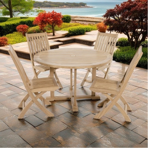 70535 Barbuda 5 piece Dining Set of 4 folding side chairs and a 48 inch round dining table side view on paver patio surrounded by shrubs overlooking the ocean in background