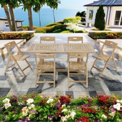 70538 Pyramid Surf teak 7 piece Dining Set of 6 folding side chairs and 72 inch rectangular dining table side view on stone patio with homes and palm trees and plants overlooking the ocean