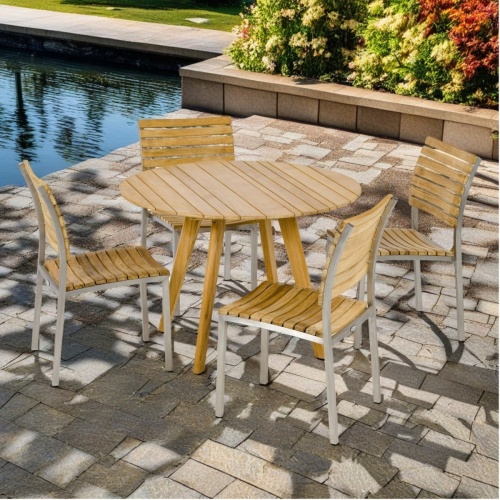 70549 Vogue Surf  Dining Set of Surf round 42 inch diameter teak dining table and 4 Teak and Stainless Steel side chairs side view on pavers with pool and flowers in background 