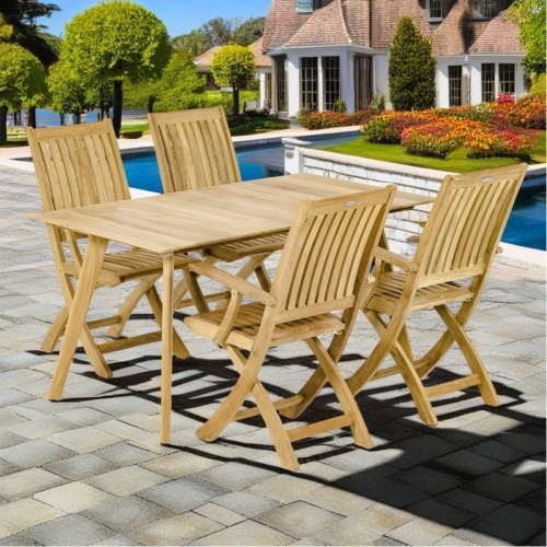 70553 Surf Barbuda Dining Set of teak 5 foot rectangular dining table and 4 Barbuda Folding Chairs on stone pool deck with landscape plants and home in background