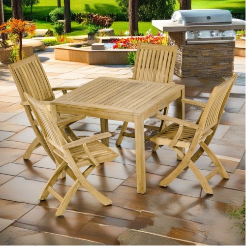 70569 Barbuda 5 pc Dining Set of Barbuda 36 inch square teak dining table and 4 Barbuda chairs angled on patio with plants in background