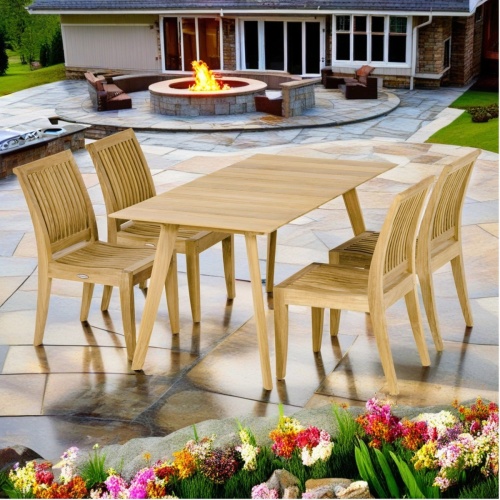 70571 Surf Laguna 5 piece Dining Set of 4 teak dining side chairs and 5 foot rectangular dining table side angled end view on stone patio with firepit and house in the background      