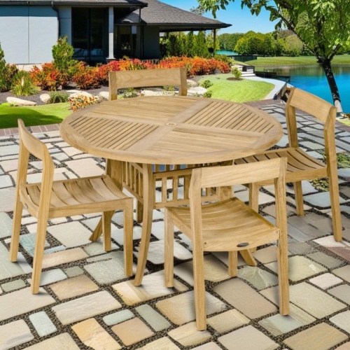 70573 Grand Hyatt Horizon Teak Dining Set of a teak 48 inch round dining table and 4 Side Chairs angled on patio overlooking a lake with trees and grass and home in background