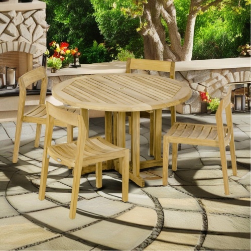 70608 Barbuda Horizon teak Dining Set of a round folding dining table and 4 Side Chairs angled view on concrete patio with bbq station and landscape trees in the background