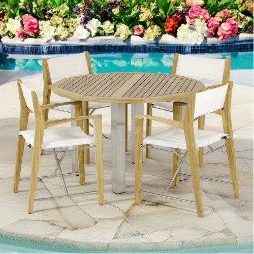 70619 Vogue Odyssey Round Dining Set of 4 folding director chairs and 48 inch round dining table angled on stone patio with pool and flowering plants in the background