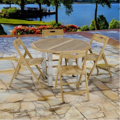 70621 Vogue Laguna Dining Set of 4 teak armchairs and a teak and stainless steel 48 inch round dining table angled side view on patio with boat dock and water in background 