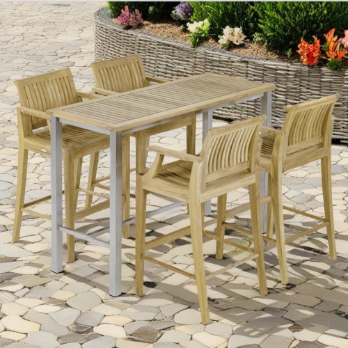 70632 Vogue Rectangular Bar Set with Laguna Barstools of Vogue stainless steel and teak rectangular table and 4 Laguna teak barstools angled on stone patio surrounded by plants in background 