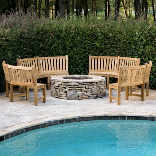 70657 Buckingham Bench Set showing 4 teak curved benches around a firepit on stone concrete patio with pool in front and bushes in background