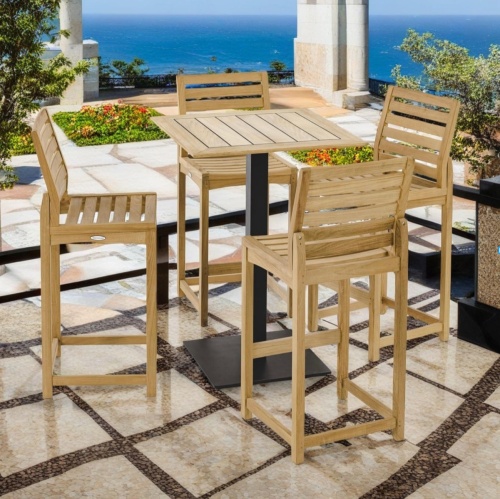 70690 Somerset 5 piece Bar Set of a Vogue 30 inch square teak and stainless steel high bar table and 4 Somerset Bar Stool aerial view on patio surrounded by trees and plants with ocean in background