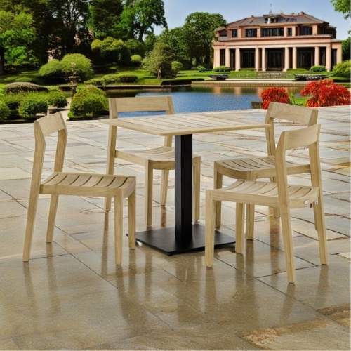 70695 Vogue Horizon 5 piece Cafe Set of 4 teak chairs and a 30 inch square teak and steel table angled view on stone patio with plants and pool and house in the background