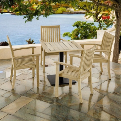70700 Sussex 5 piece Dining Set of 4 teak dining armchairs and 30 inch square dining table angled view on stone terrace overlooking lake with trees and boat docks in background