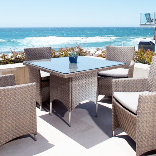 70708 Summer Grass 5 piece Dining Set of 4 Dining Chairs with cushions and square dining table on outdoor terrace surrounded by landscape plants overlooking the ocean and blue sky