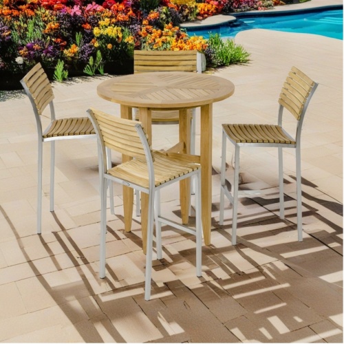 70722 Somerset 36 inch diameter Round Pub table and 4 Vogue Side Bar Stools angled on paver pool deck with flowering plants and partial pool view in  the background     