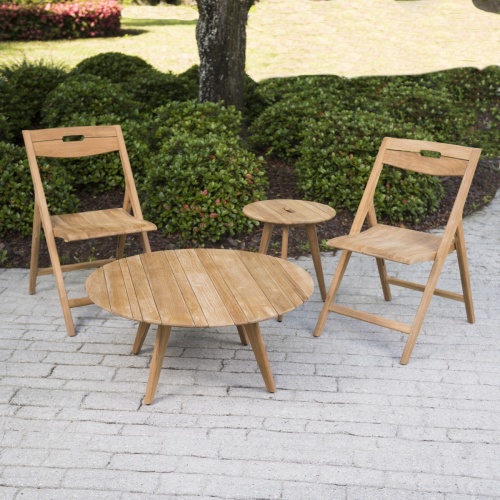  70730 surf four piece teak chat set on stone paver patio with bushes around a tree with grass lawn in background