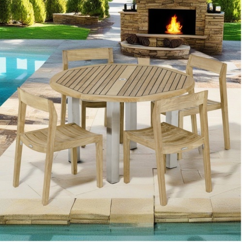 70738 Vogue Horizon 5 piece teak and stainless steel Dining Set of 4 teak chairs and a teak and stainless steel 48 inch round dining table on pavers next to pool fireplace in background