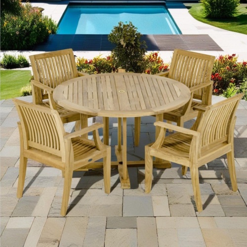 70746 Laguna round Dining Set of 4 teak armchairs and round 48 inch diameter dining table angled on paver patio with landscape plants and pool in background