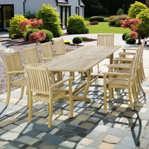 70758 Sussex Veranda 11 piece teak dining set of 10 teak dining armchairs and rectangular dining table angled on patio with plants and house in background 