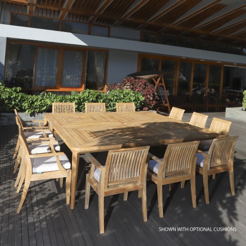 70801 Pyramid Laguna Teak Square 13 piece Dining Set with optional seat cushions on a covered wood deck patio with shrubs and a building in background