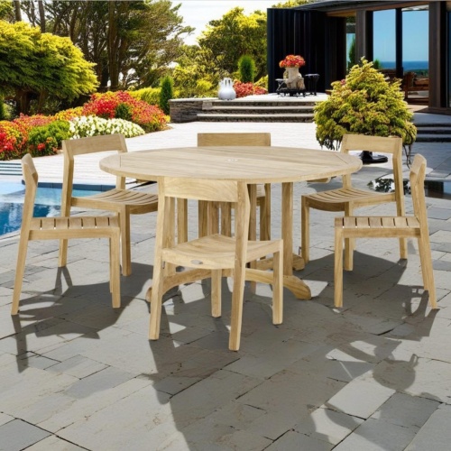 70847 Barbuda Horizon 7 piece Teak Dining Set of 6 teak side chairs and a 5 foot Round Teak folding dining table on pool deck surrounded by trees and plants with house in background