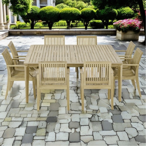 70867 Square Veranda Laguna 9 piece Dining Set of 8 teak dining armchairs and 6 foot square dining table side view on stone patio with trees and shrubs in background  