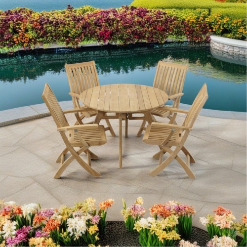 70919 Barbuda Surf 4 piece Cafe Dining Set of teak 42 inch round dining table and 4 folding side chairs angled aerial view on a pool deck surrounded by spring flowers and lake in the far background 