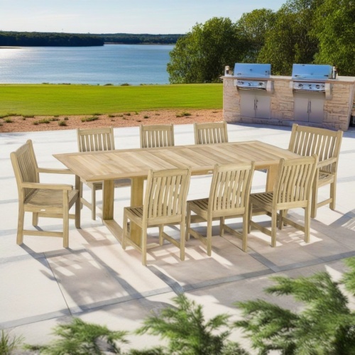 70925 Horizon Veranda teak rectangular dining set of Horizon rectangular table and 6 Veranda Side Chairs and 2 Armchairs angled on stone patio with grass lawn and lake in the background